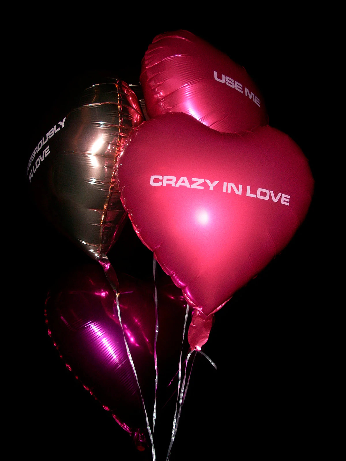 Cluster of heart-shaped balloons in pink, purple, and gold with romantic phrases