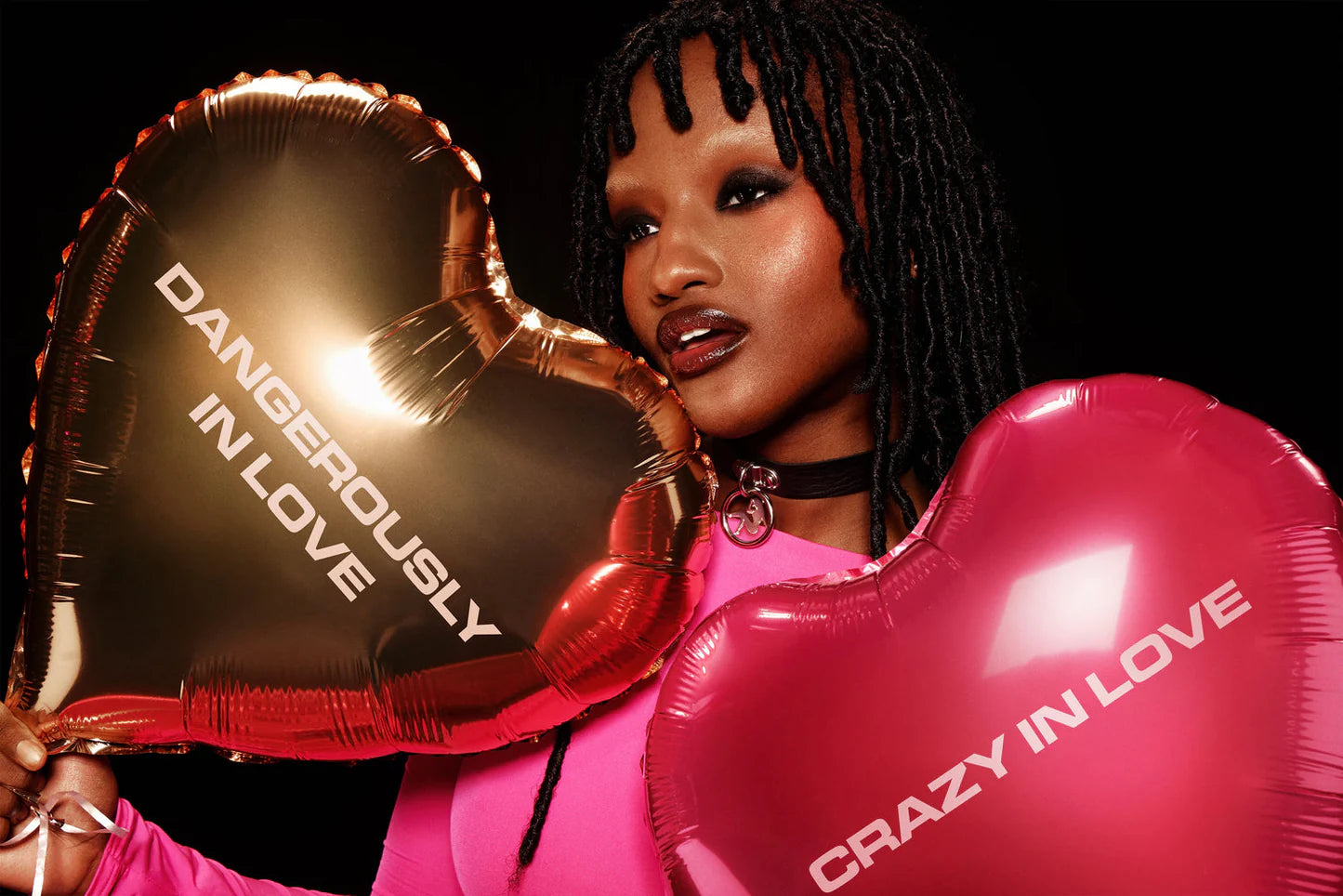 Model holding gold “dangerously in love” and pink “crazy in love” heart balloons